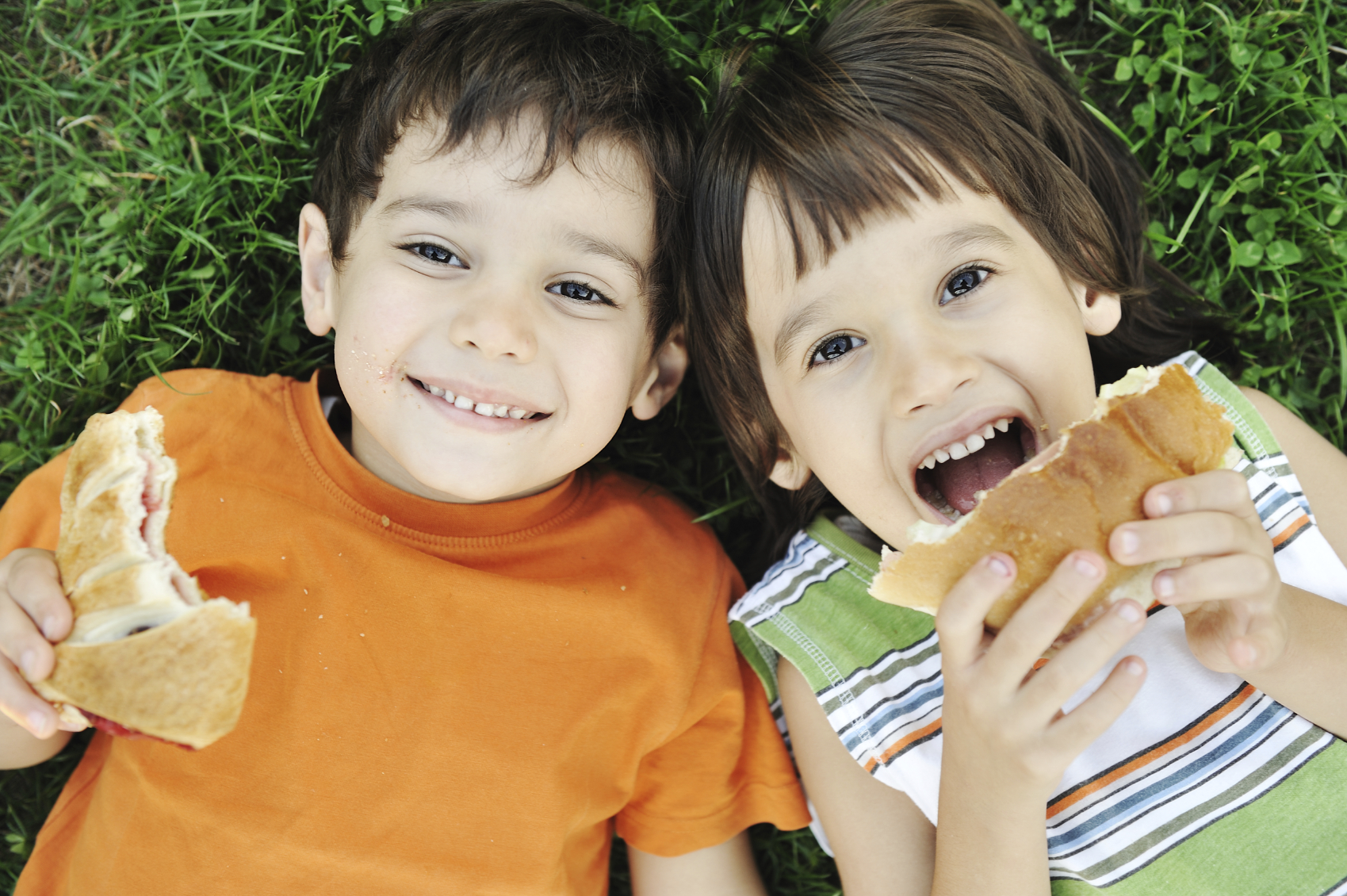 Two Women And A Toddler Eating Lunch In The Park Sitting On A Blanket